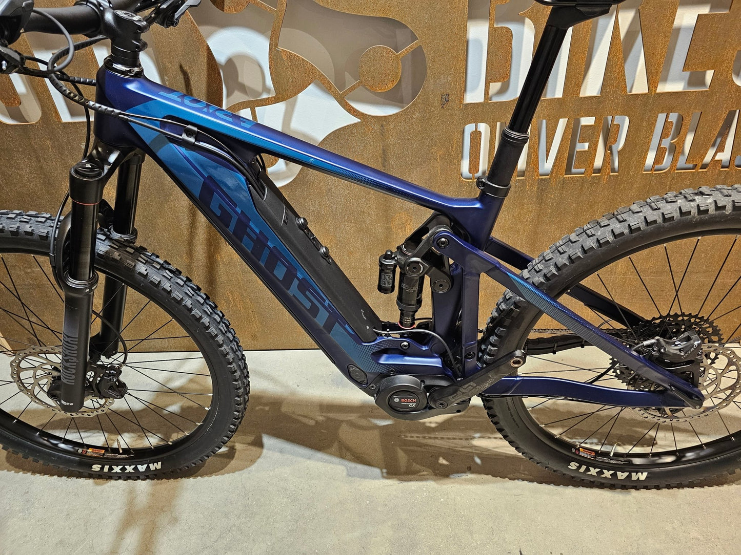 E - Mountainbike von Ghost, GHOST E - RIOT TRAIL CF ADVANCED / S in variant_title vor USEDBIKES - OB.DE Hintergrund