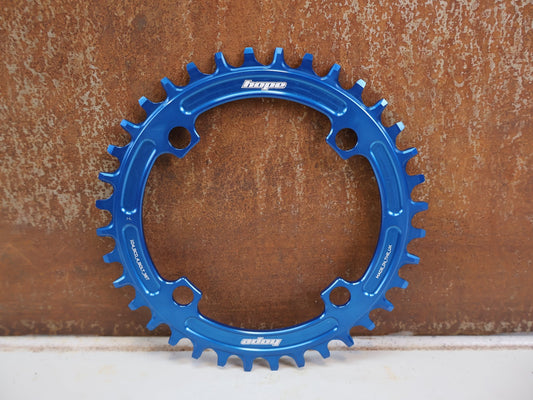 Kettenblatt von Hope, HOPE KETTENBLATT 104 BCD 36 ZÄHNE BLAU 4-ARM RR3622B vor USEDBIKES-OB.DE Hintergrund