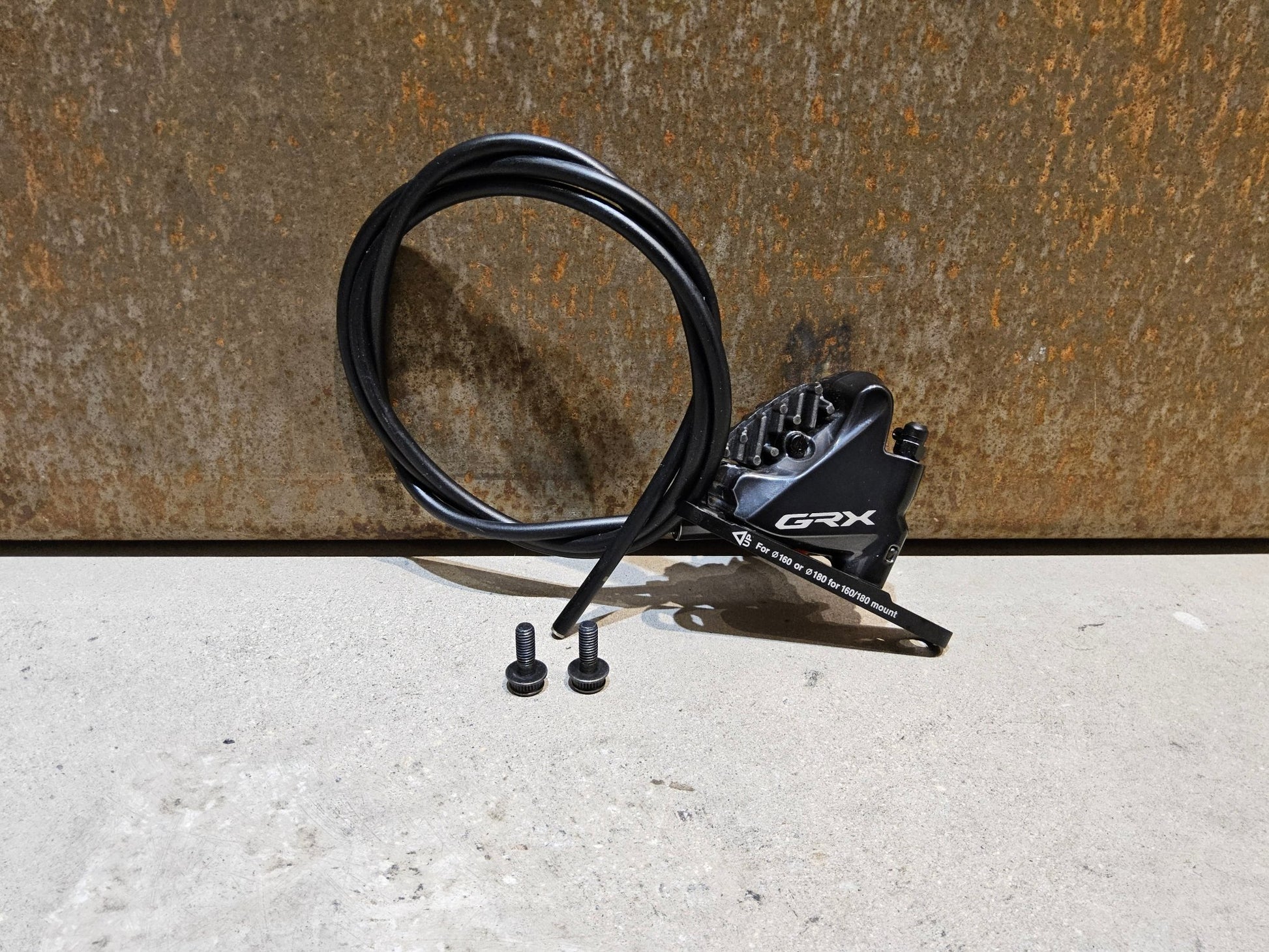 Bremse von Shimano, SHIMANO GRX BREMSSATTEL BR - RX810 - F / - R FLATMOUNT VORNE / HINTEN INKL. LEITUNG in variant_title vor USEDBIKES - OB.DE Hintergrund