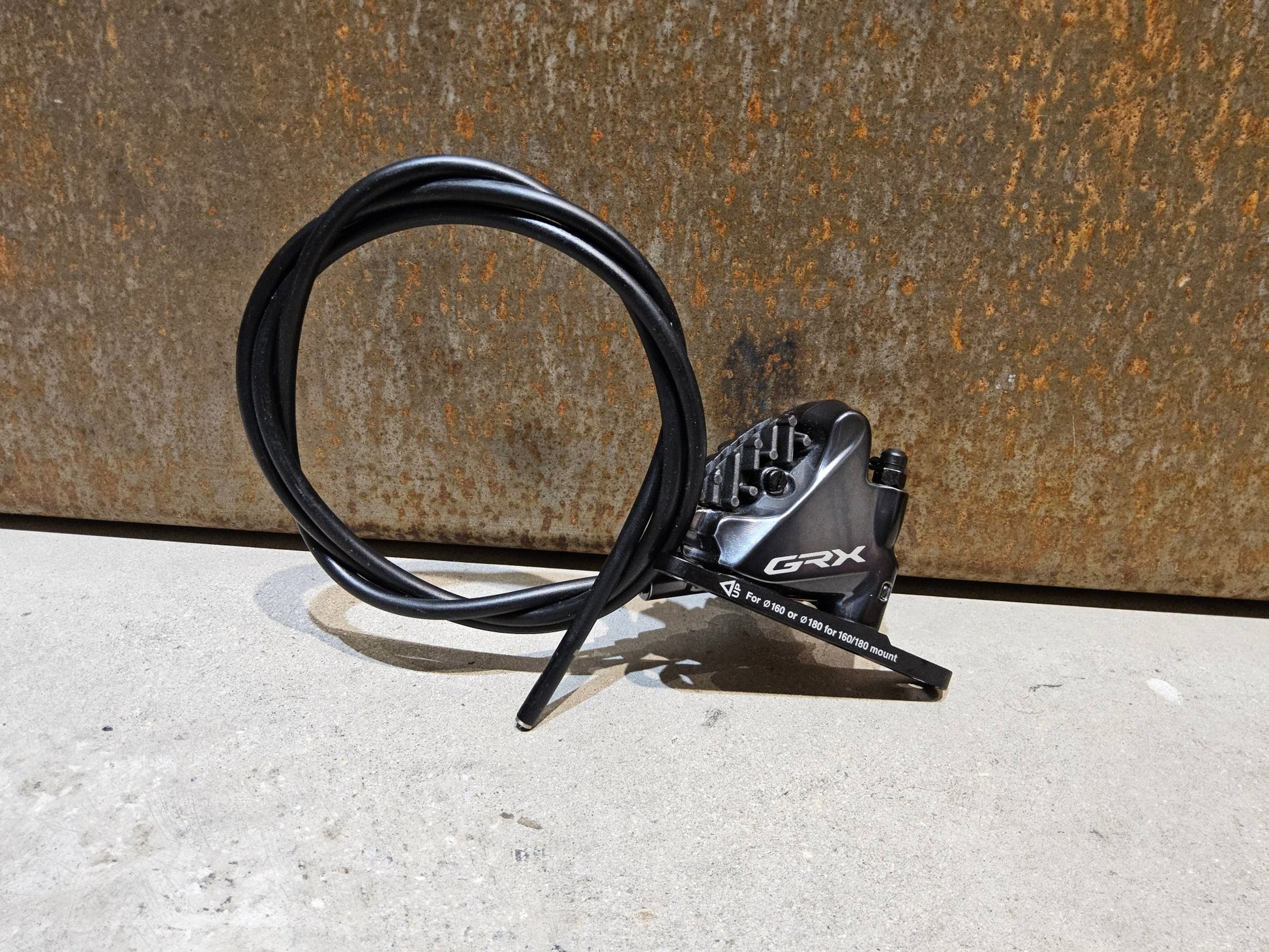 Bremse von Shimano, SHIMANO GRX BREMSSATTEL BR - RX810 - F / - R FLATMOUNT VORNE / HINTEN INKL. LEITUNG in variant_title vor USEDBIKES - OB.DE Hintergrund