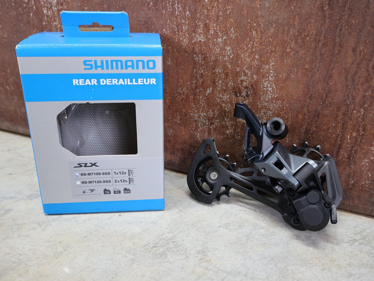 Schaltungsteile von Shimano, SHIMANO SLX RD - M7100 - SGS SCHALTWERK 12 FACH vor USEDBIKES - OB.DE Hintergrund