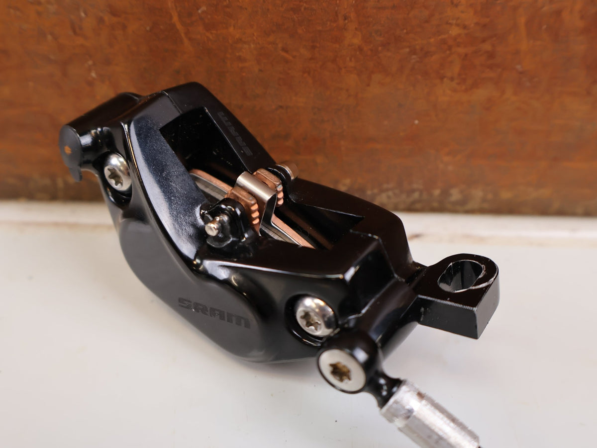 Bremse von Sram, SRAM Code Silver Stealth Bremssattel 4-Kolben Black vor USEDBIKES-OB.DE Hintergrund