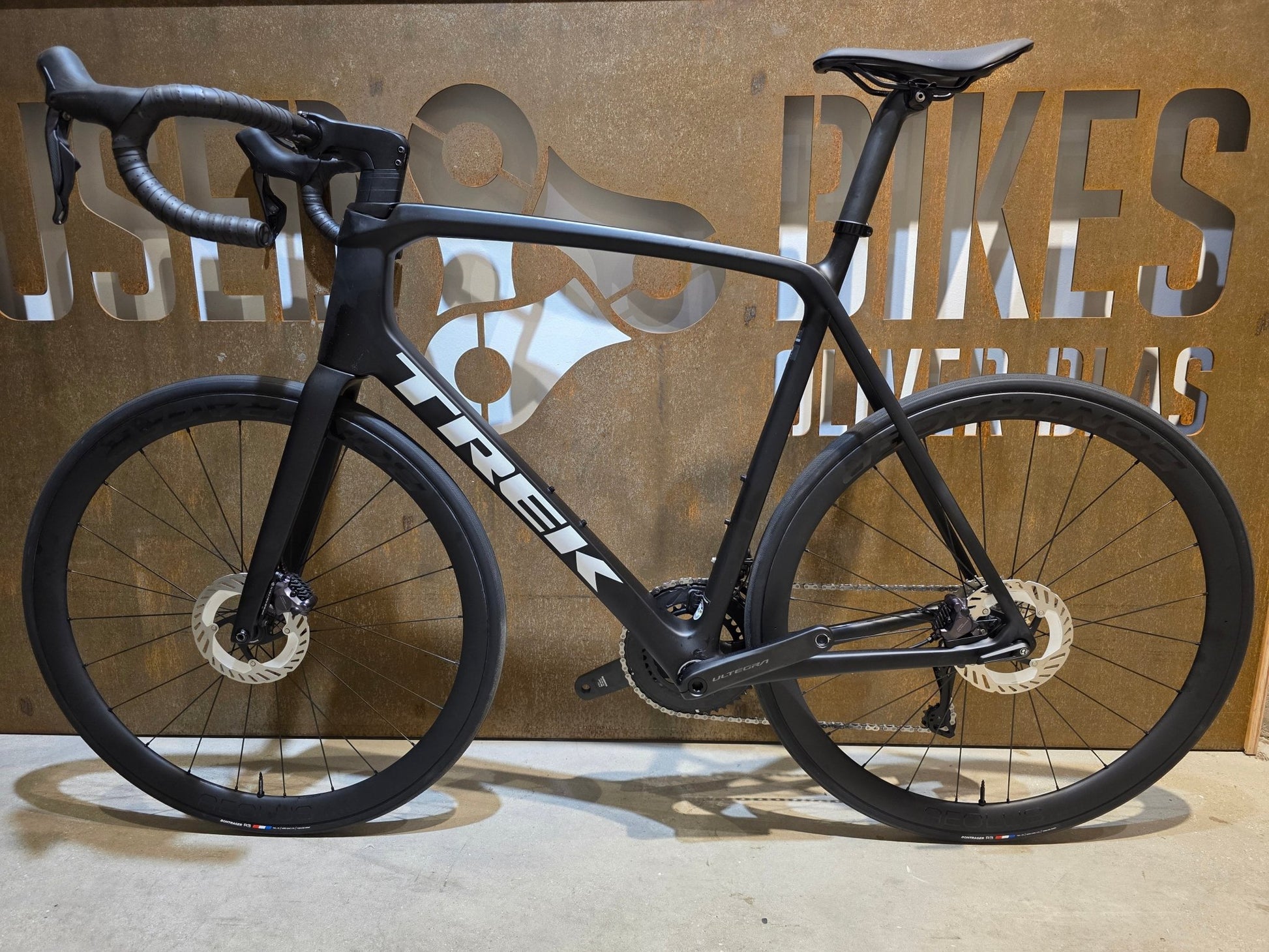 Rennrad von Trek, TREK EMONDA SL 7 / MATTE CARBON SMOKE / 62CM in variant_title vor USEDBIKES - OB.DE Hintergrund
