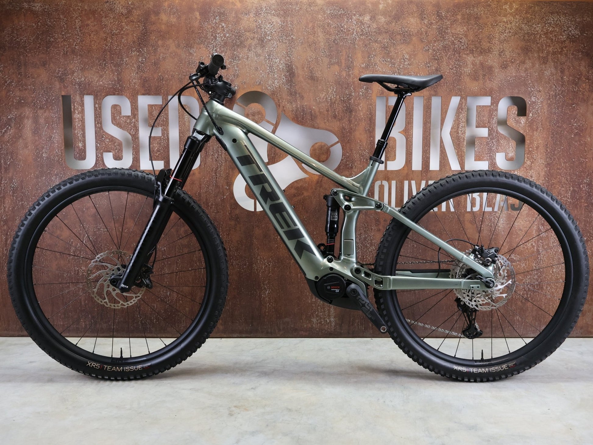 E - Mountainbike von Trek, TREK RAIL 7 DEORE/XT GEN 3 / LICHEN GREEN / L vor USEDBIKES - OB.DE Hintergrund