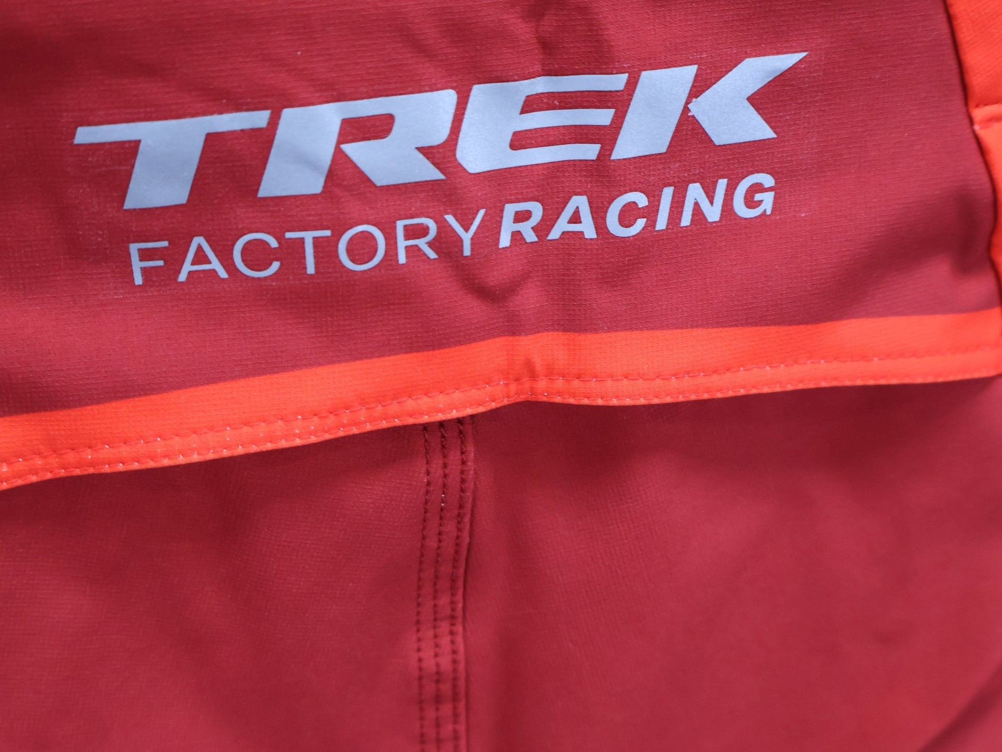 Hosen Herren von 100%, 100% – R - CORE X PANTS / ORANGE - RED / TREK FACTORY RACING TEAM / 4 - WAY STRETCH vor USEDBIKES - OB.DE Hintergrund