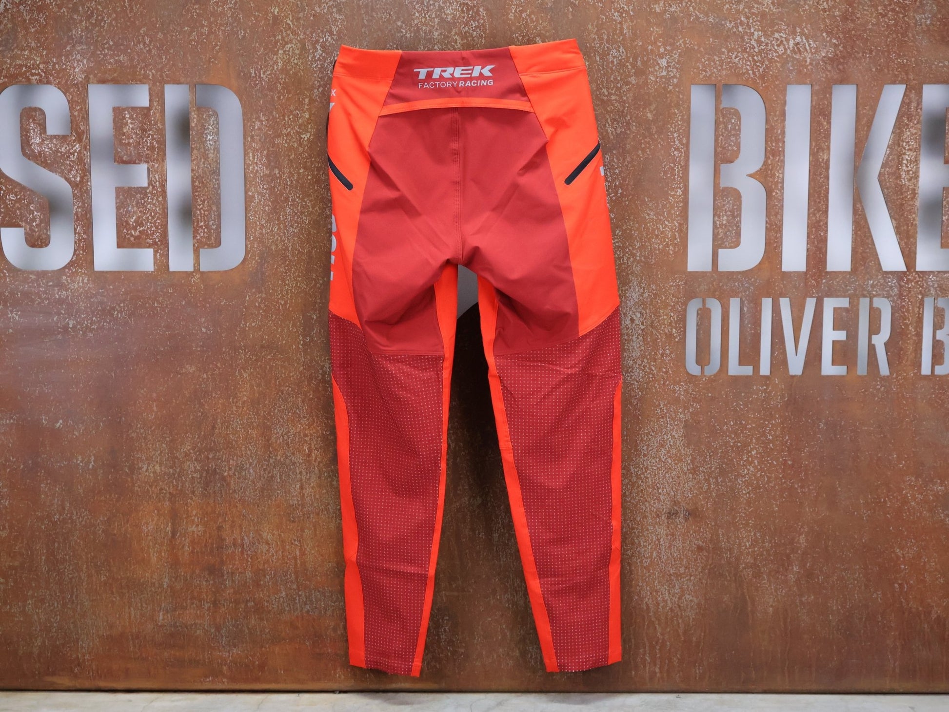 Hosen Herren von 100%, 100% – R - CORE X PANTS / ORANGE - RED / TREK FACTORY RACING TEAM / 4 - WAY STRETCH vor USEDBIKES - OB.DE Hintergrund
