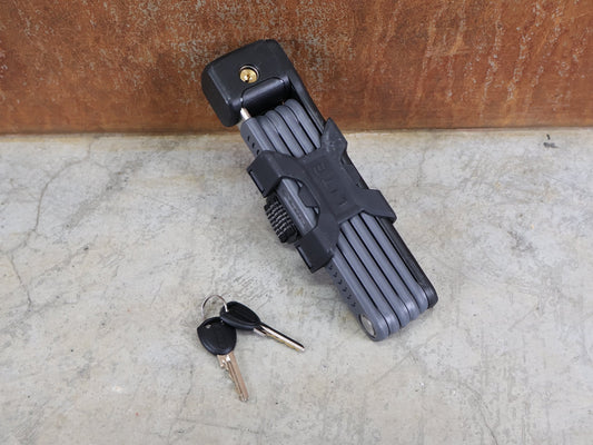 Fahrradschlösser von Abus, ABUS BORDO LITE 6055 MINI / 85 CM – FALTSCHLOSS – SECURITY LEVEL 7 – INKL. SH 6055 HALTER – SCHWARZ vor USEDBIKES - OB.DE Hintergrund