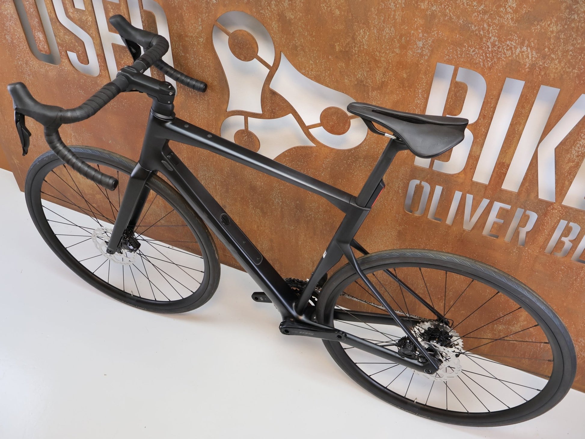 Rennrad von Bmc, BMC ROADMACHINE TWO / GRÖSSE 56 / SHIMANO 105 DI2 / CARBON BLACK vor USEDBIKES - OB.DE Hintergrund