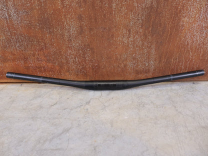 Lenker von Bontrager, BONTRAGER KOVEE XXX CARBON 35 MTB - LENKER – 700 MM – 0 MM RISE – CARBON SMOKE vor USEDBIKES - OB.DE Hintergrund