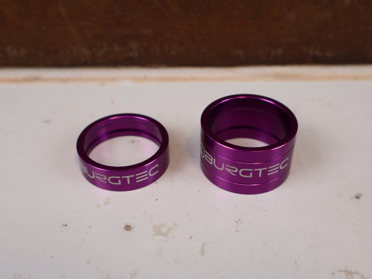 Vorbau von Burgtec, Burgtec Spacer Set Top Cap + Bolt Purple Rain Schwarz vor USEDBIKES-OB.DE Hintergrund
