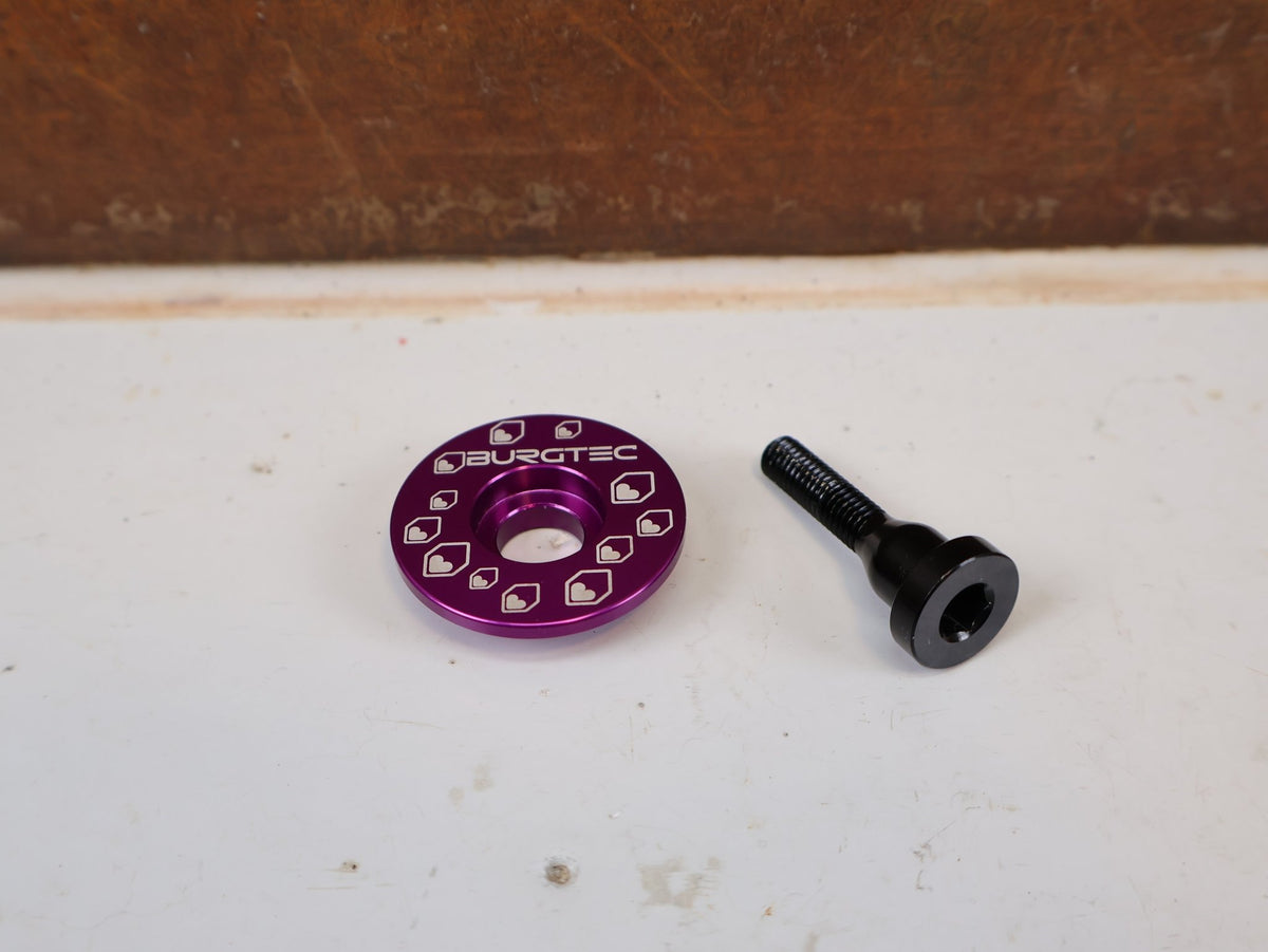 Vorbau von Burgtec, Burgtec Spacer Set Top Cap + Bolt Purple Rain Schwarz vor USEDBIKES-OB.DE Hintergrund