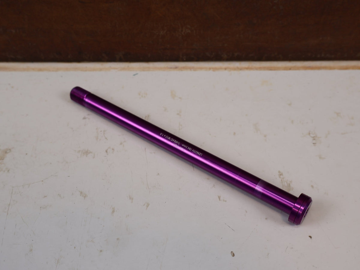 Zubehör von Burgtec, Burgtec Trek Steckachse 184.5mm M12x1.0 Purple Rain 10104 vor USEDBIKES-OB.DE Hintergrund