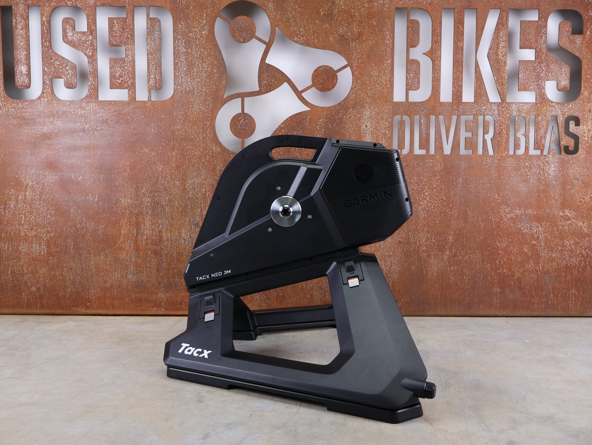 Rollentrainer & Zubehör von Garmin, GARMIN TACX NEO 3M HEIMTRAINER – SMART TRAINER MIT DIREKTANTRIEB vor USEDBIKES - OB.DE Hintergrund