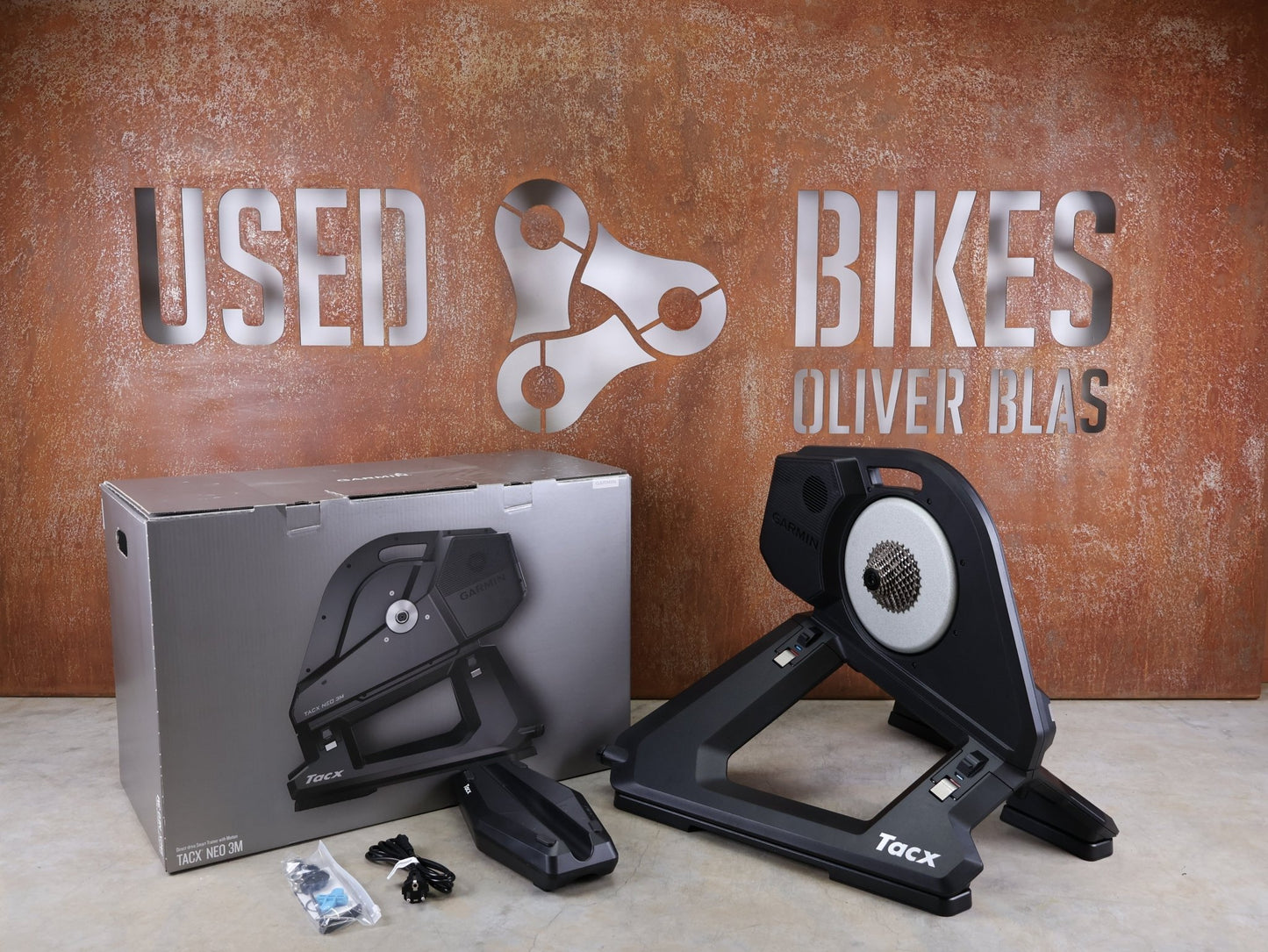 Rollentrainer & Zubehör von Garmin, GARMIN TACX NEO 3M HEIMTRAINER – SMART TRAINER MIT DIREKTANTRIEB vor USEDBIKES - OB.DE Hintergrund