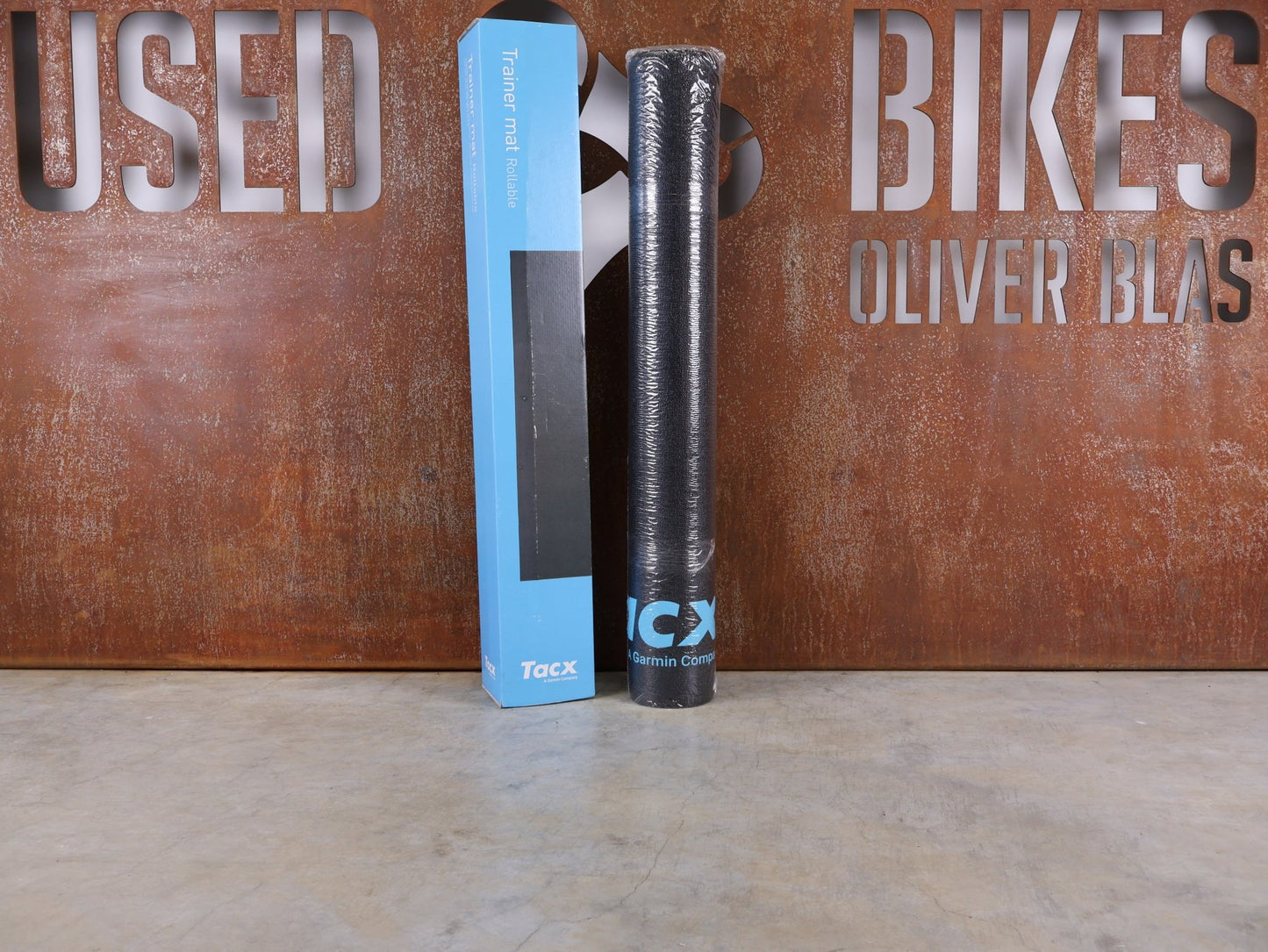 Rollentrainer & Zubehör von Garmin, GARMIN TACX TRAINERMATTE T2918 – ROLLBAR vor USEDBIKES - OB.DE Hintergrund