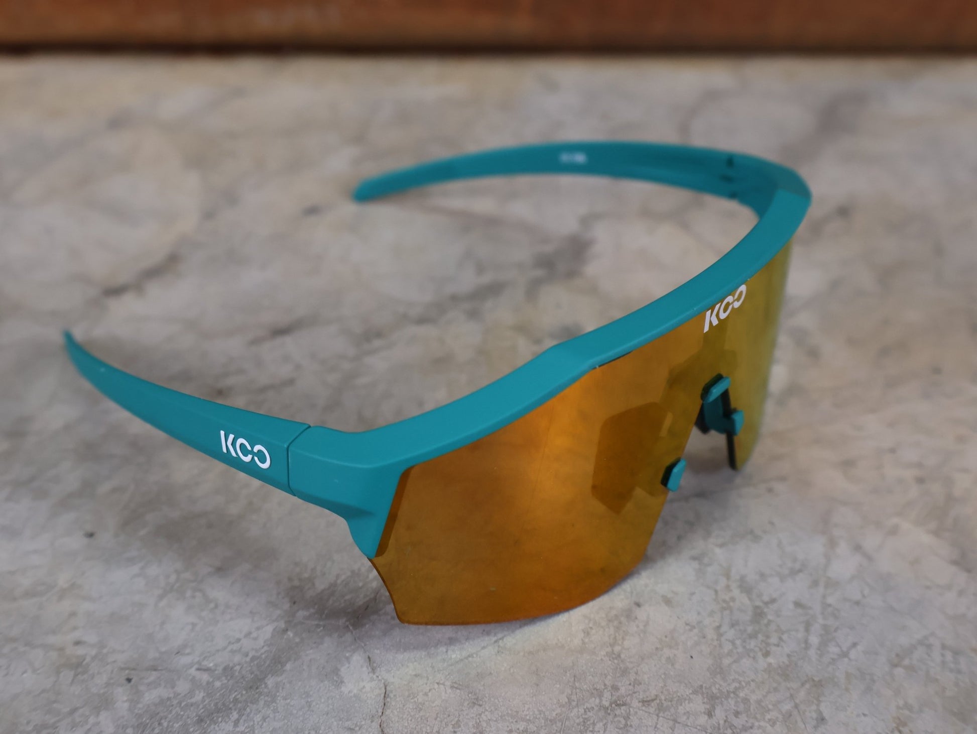 Brillen von Koo, KOO ALIBI BRILLE – PERSIAN GREEN MATT / ORANGE MIRROR vor USEDBIKES - OB.DE Hintergrund