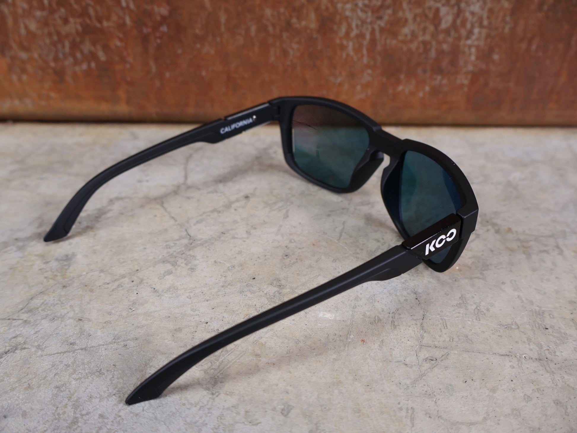 Brillen von Koo, KOO CALIFORNIA BRILLE – SCHWARZ MATT / RED MIRROR – RED BULL – BORA – HANSGROHE EDITION vor USEDBIKES - OB.DE Hintergrund