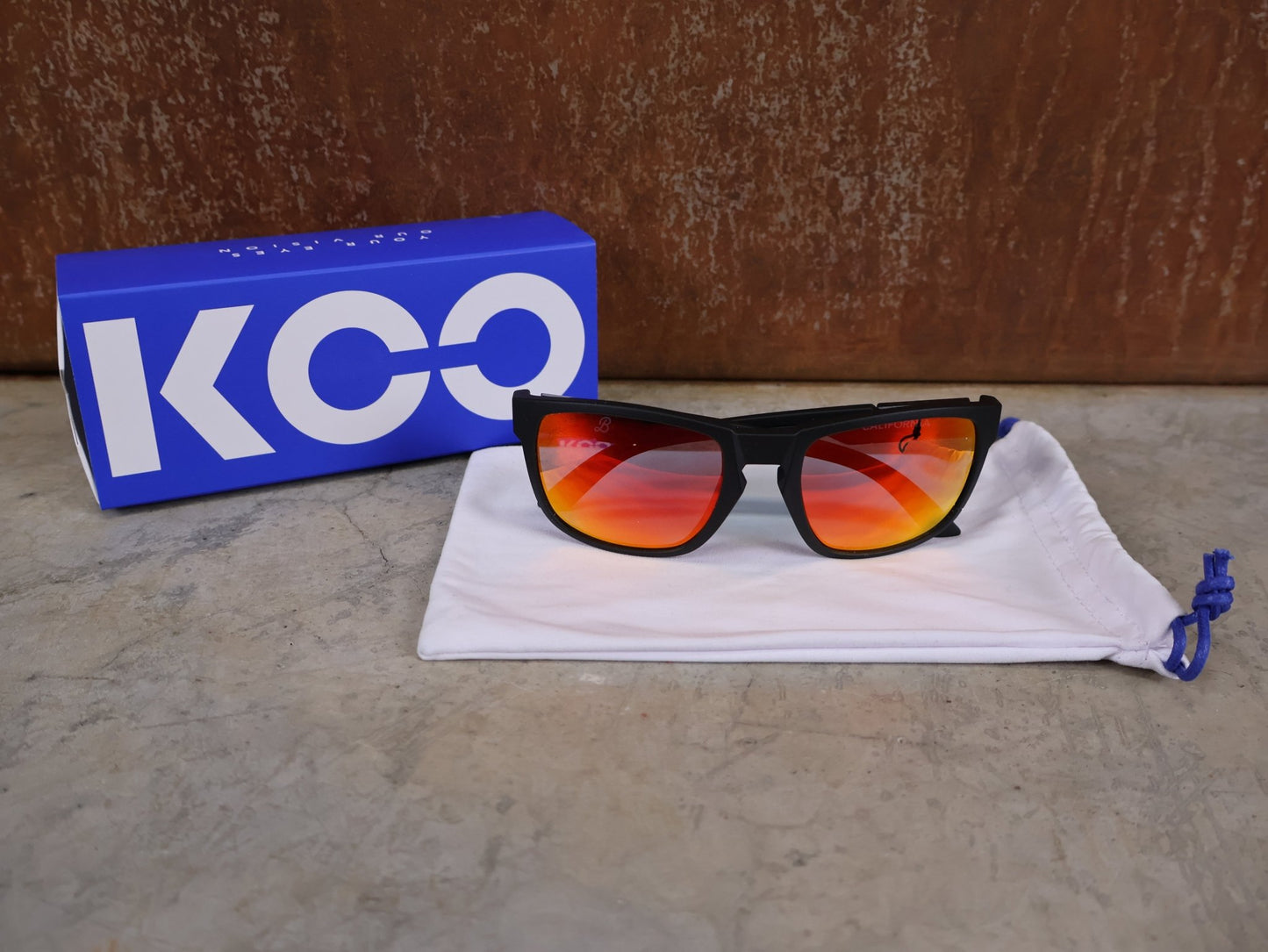 Brillen von Koo, KOO CALIFORNIA BRILLE – SCHWARZ MATT / RED MIRROR – RED BULL – BORA – HANSGROHE EDITION vor USEDBIKES - OB.DE Hintergrund