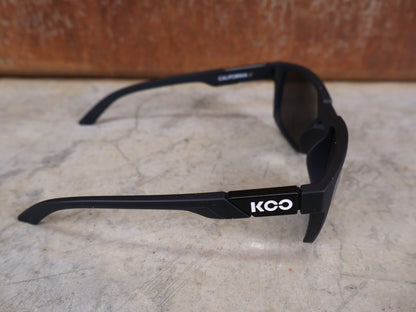 Brillen von Koo, KOO CALIFORNIA BRILLE – SCHWARZ MATT / SUPER SILVER – RED BULL – BORA – HANSGROHE EDITION vor USEDBIKES - OB.DE Hintergrund