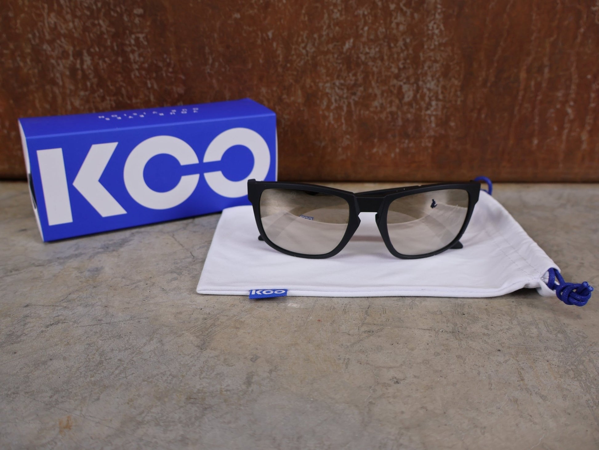 Brillen von Koo, KOO CALIFORNIA BRILLE – SCHWARZ MATT / SUPER SILVER – RED BULL – BORA – HANSGROHE EDITION vor USEDBIKES - OB.DE Hintergrund