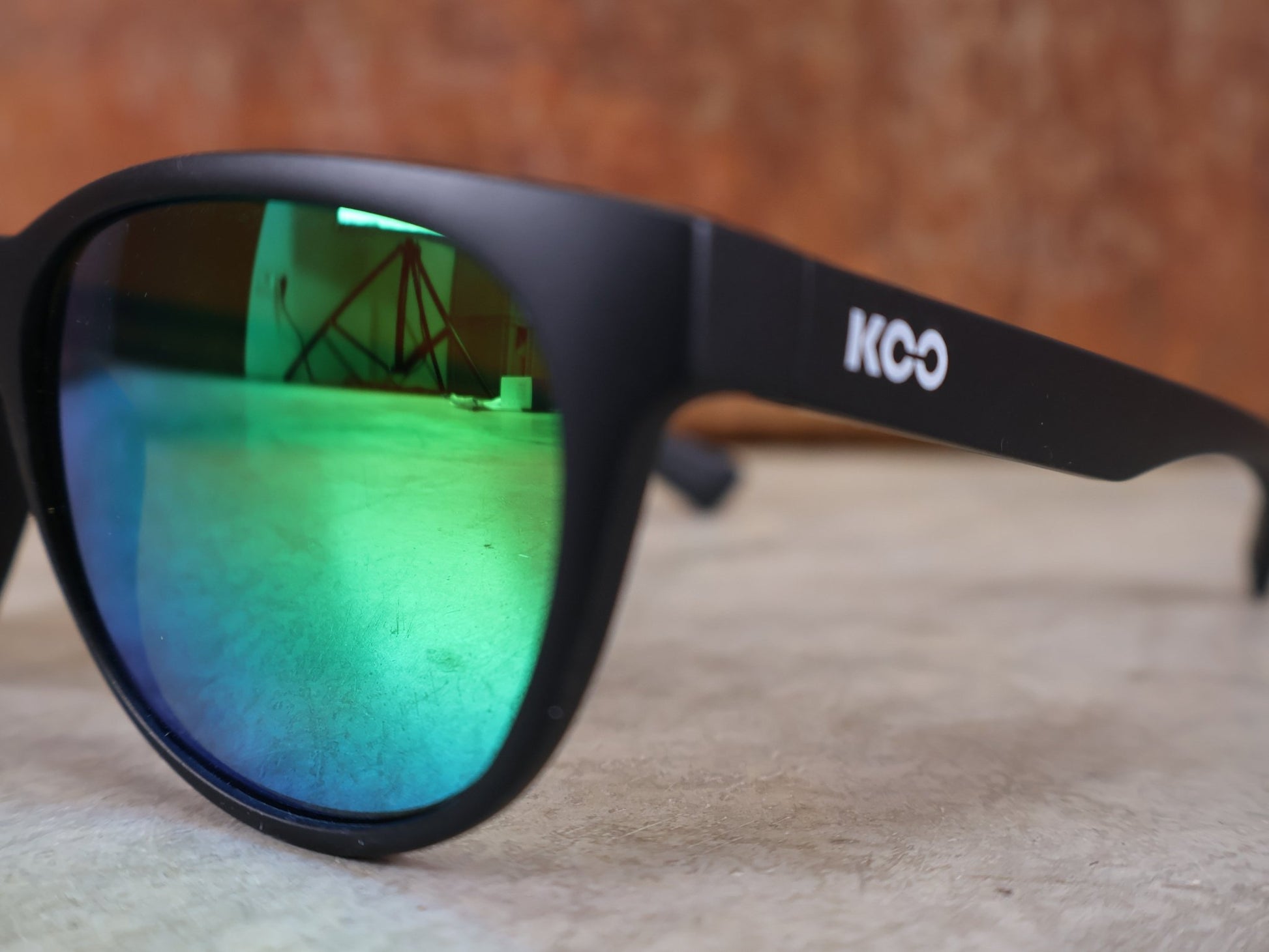 Brillen von Koo, KOO COSMO BRILLE – SCHWARZ MATT / GREEN MIRROR – RED BULL – BORA – HANSGROHE EDITION vor USEDBIKES - OB.DE Hintergrund