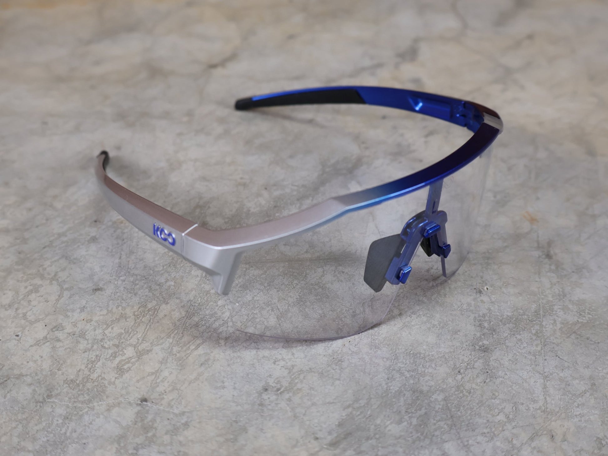 Brillen von Koo, KOO RED BULL - BORA HANSGROHE ALIBI LARGE SONNENBRILLE / CLEAR SMOKE vor USEDBIKES - OB.DE Hintergrund