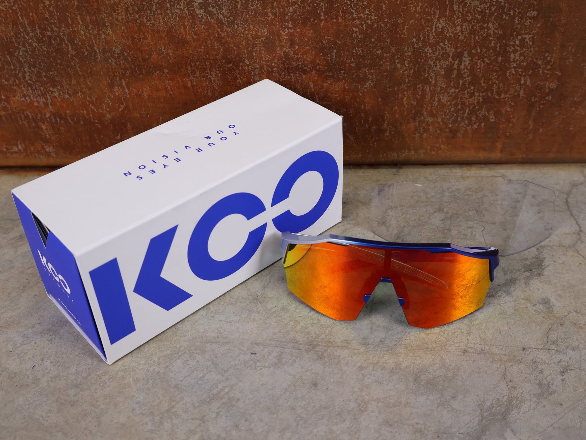 Brillen von Koo, KOO RED BULL - BORA HANSGROHE ALIBI LARGE SONNENBRILLE / RED MIRROR vor USEDBIKES - OB.DE Hintergrund