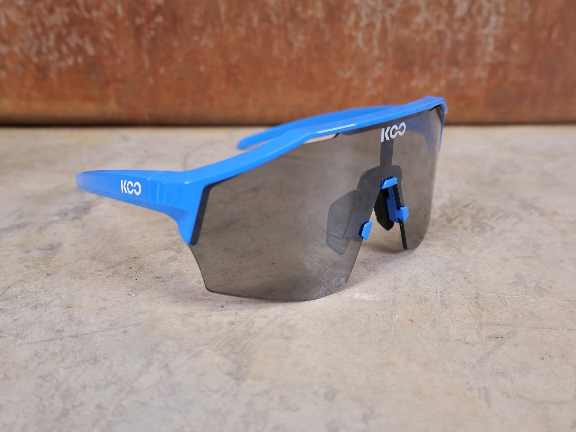 Brillen von Koo, KOO RED BULL - BORA HANSGROHE ALIBI PRO SONNENBRILLE / BLUE JERSEY vor USEDBIKES - OB.DE Hintergrund