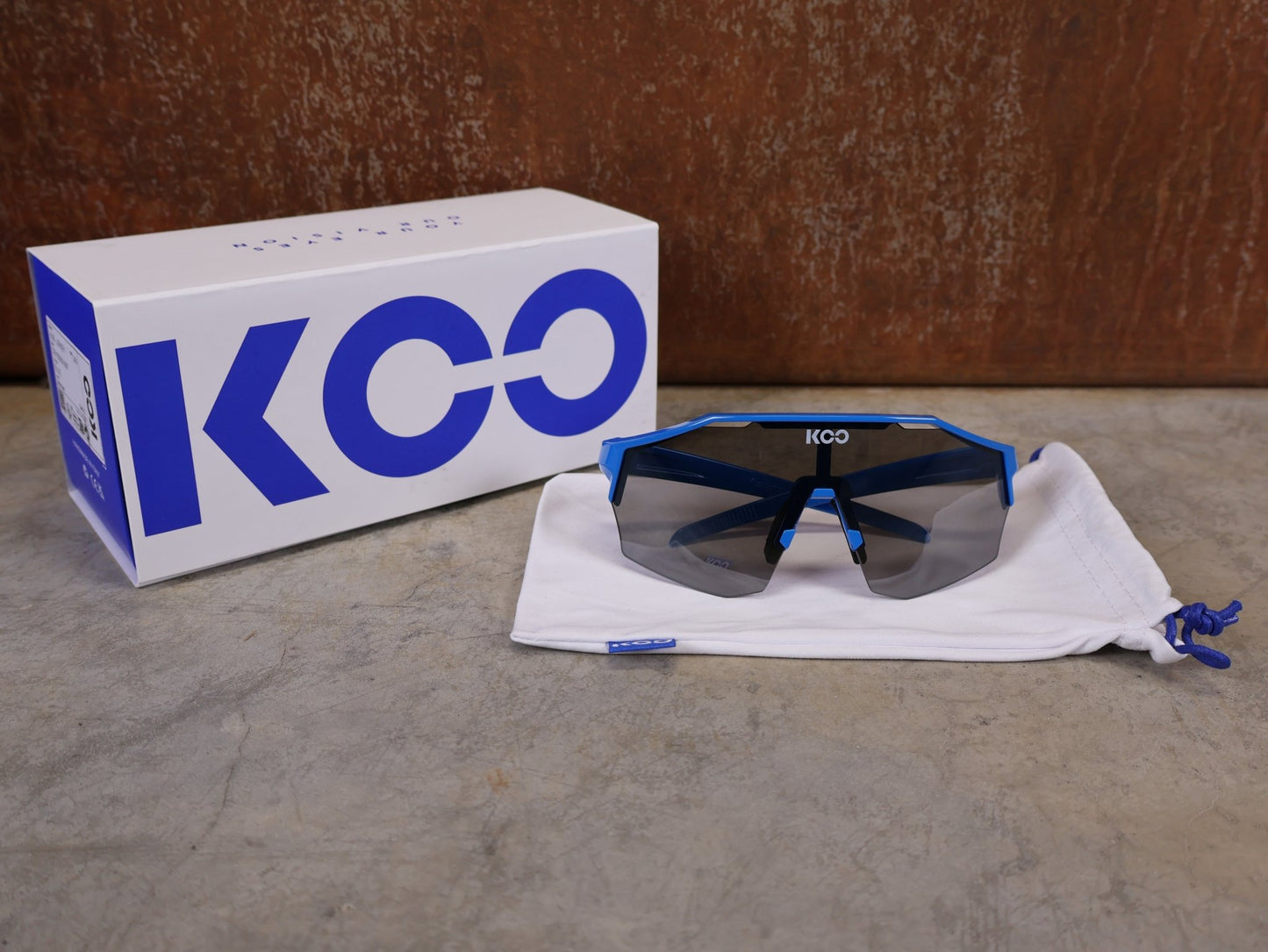 Brillen von Koo, KOO RED BULL - BORA HANSGROHE ALIBI PRO SONNENBRILLE / BLUE JERSEY vor USEDBIKES - OB.DE Hintergrund