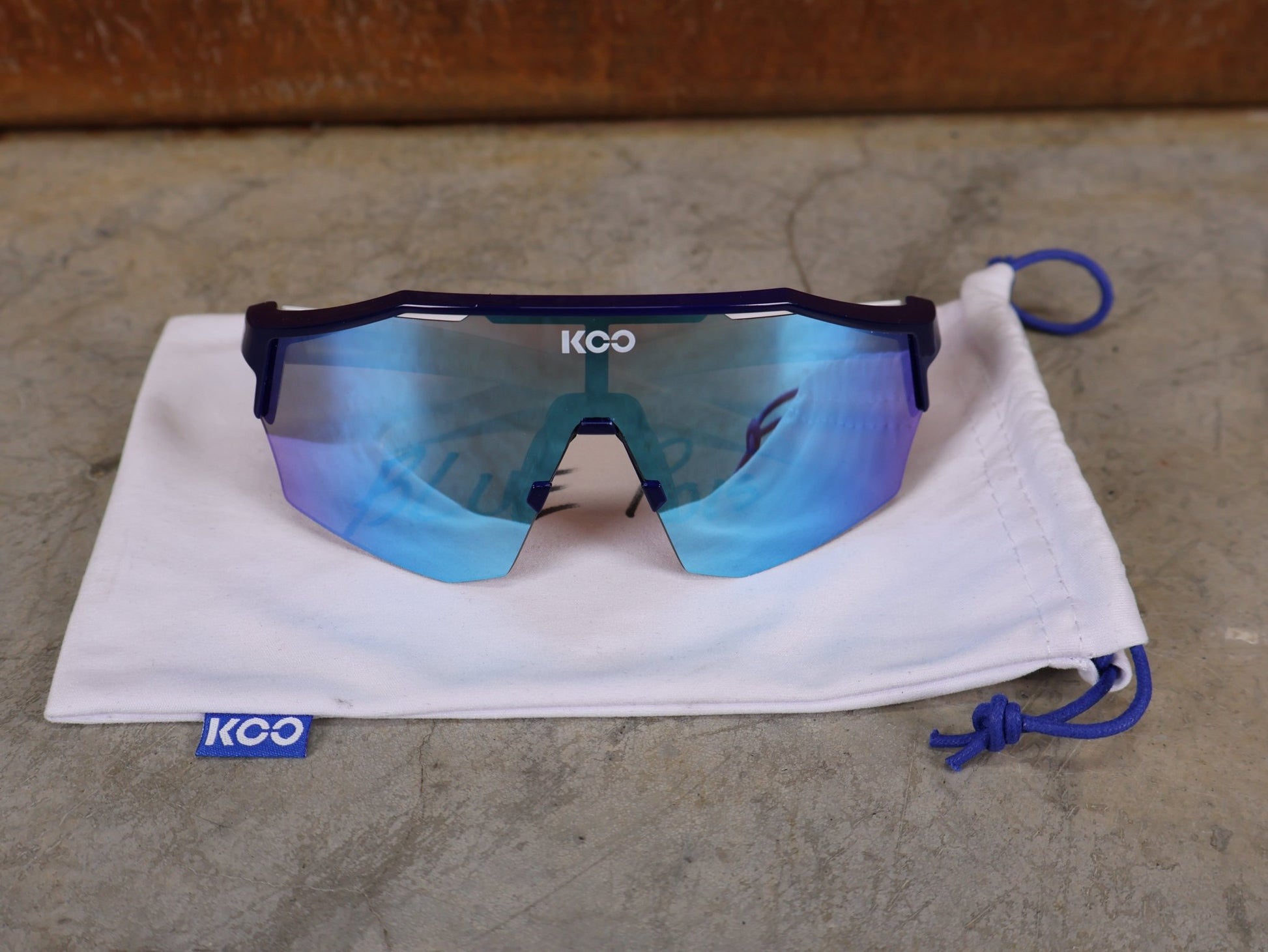 Brillen von Koo, KOO RED BULL - BORA HANSGROHE ALIBI SONNENBRILLE / LEADER EDITION BLAU vor USEDBIKES - OB.DE Hintergrund