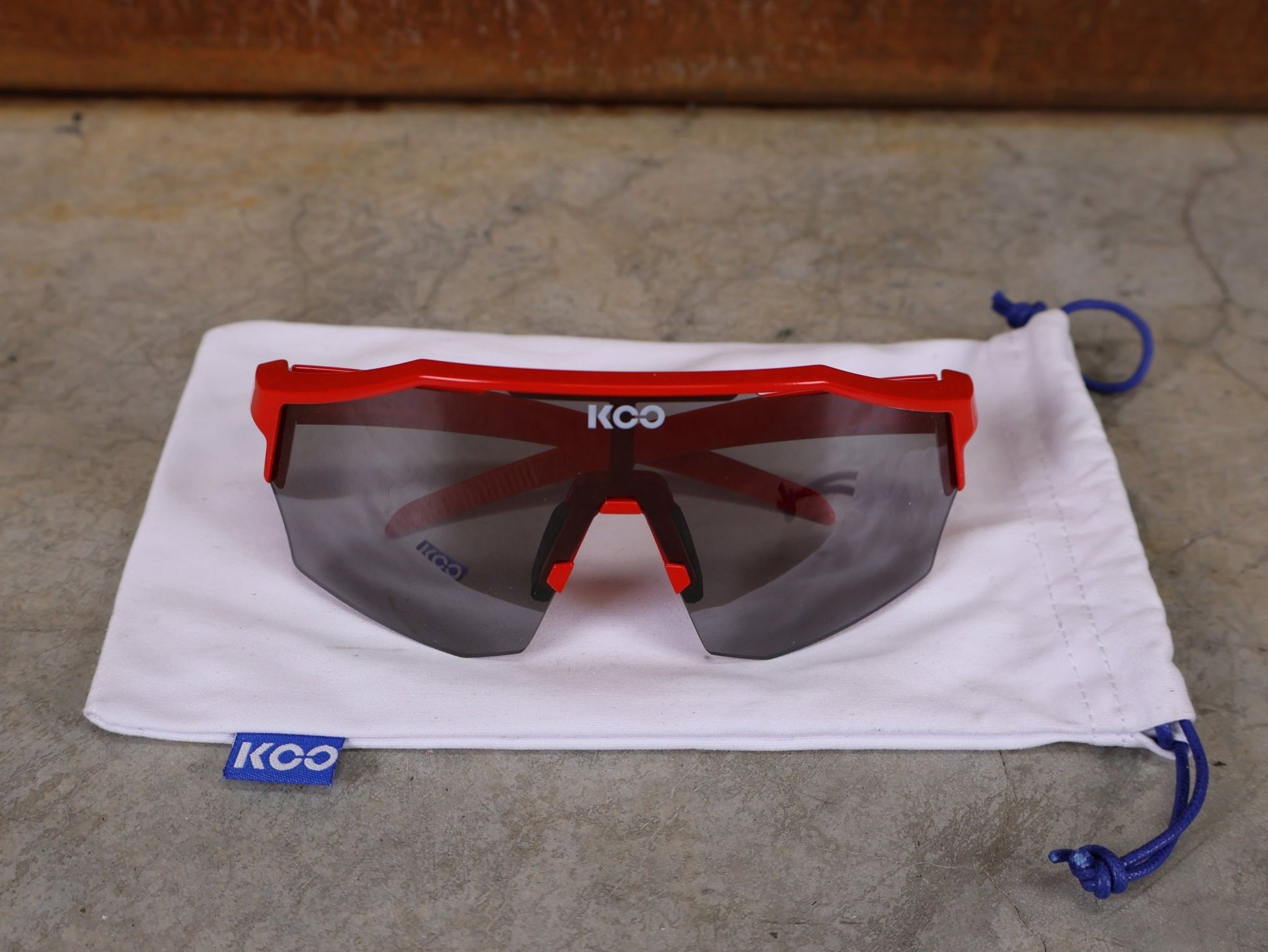 Brillen von Koo, KOO RED BULL - BORA HANSGROHE ALIBI SONNENBRILLE / LEADER EDITION ROT vor USEDBIKES - OB.DE Hintergrund