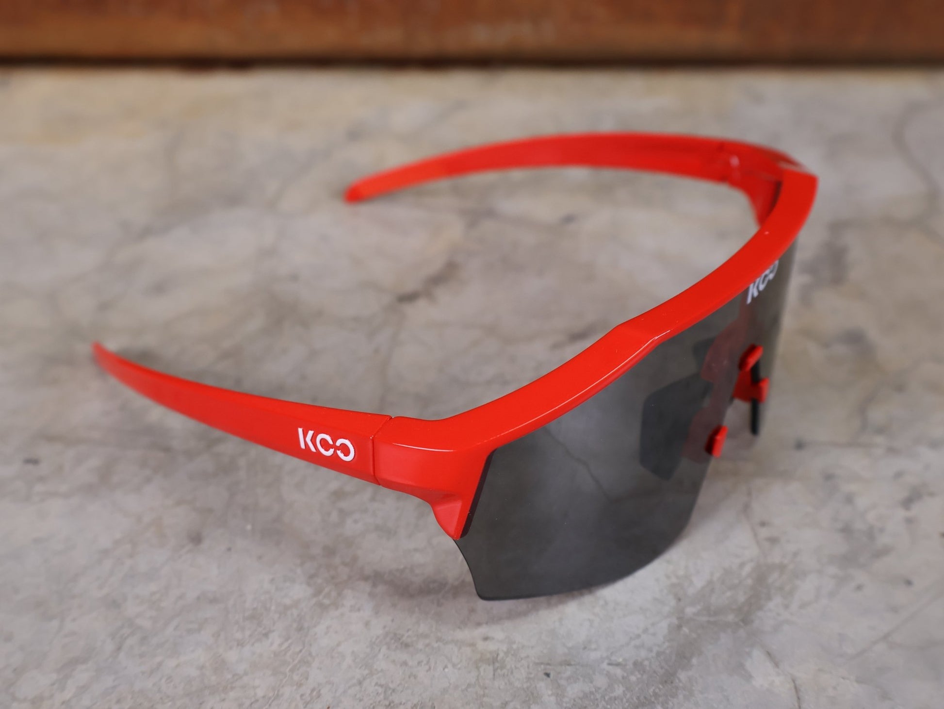 Brillen von Koo, KOO RED BULL - BORA HANSGROHE ALIBI SONNENBRILLE / LEADER EDITION ROT vor USEDBIKES - OB.DE Hintergrund