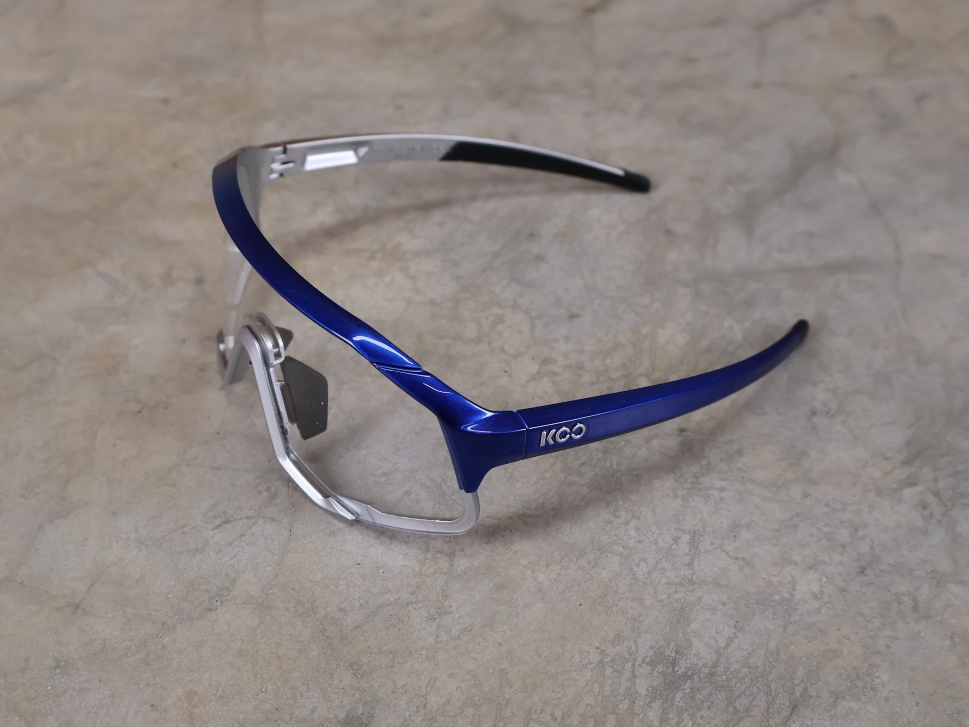 Brillen von Koo, KOO RED BULL - BORA HANSGROHE DEMOS SONNENBRILLE / CLEAR SMOKE vor USEDBIKES - OB.DE Hintergrund