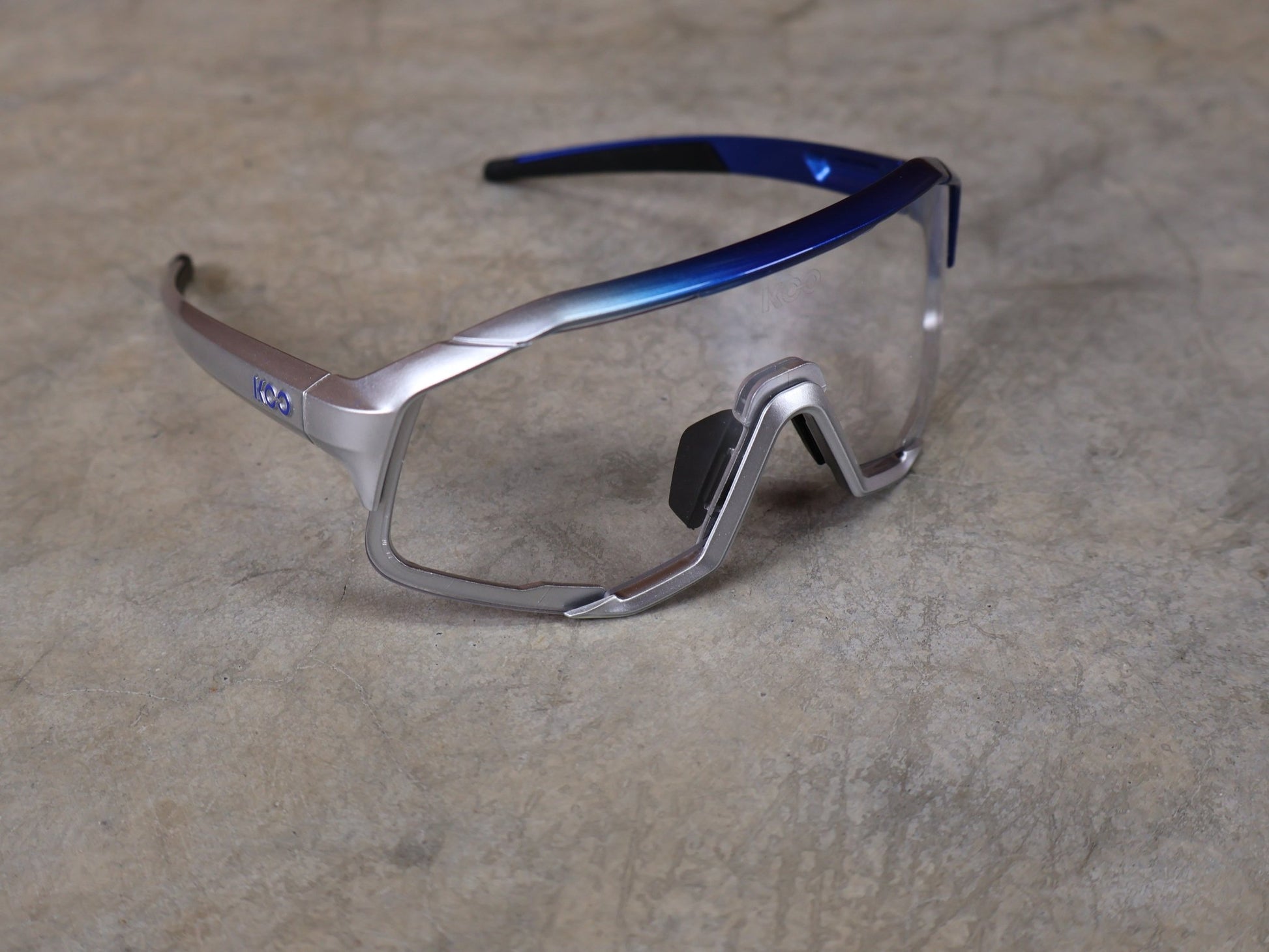 Brillen von Koo, KOO RED BULL - BORA HANSGROHE DEMOS SONNENBRILLE / CLEAR SMOKE vor USEDBIKES - OB.DE Hintergrund