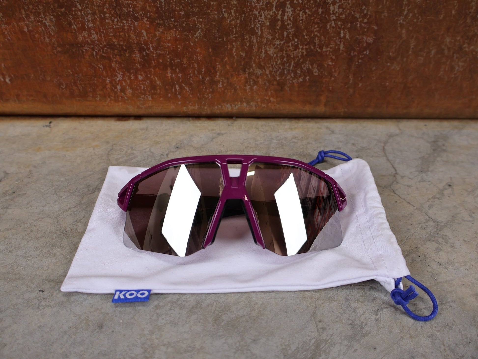 Brillen von Koo, KOO RED BULL - BORA HANSGROHE HYPE SONNENBRILLE / LEADER EDITION LILA vor USEDBIKES - OB.DE Hintergrund