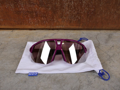 Brillen von Koo, KOO RED BULL - BORA HANSGROHE HYPE SONNENBRILLE / LEADER EDITION LILA vor USEDBIKES - OB.DE Hintergrund
