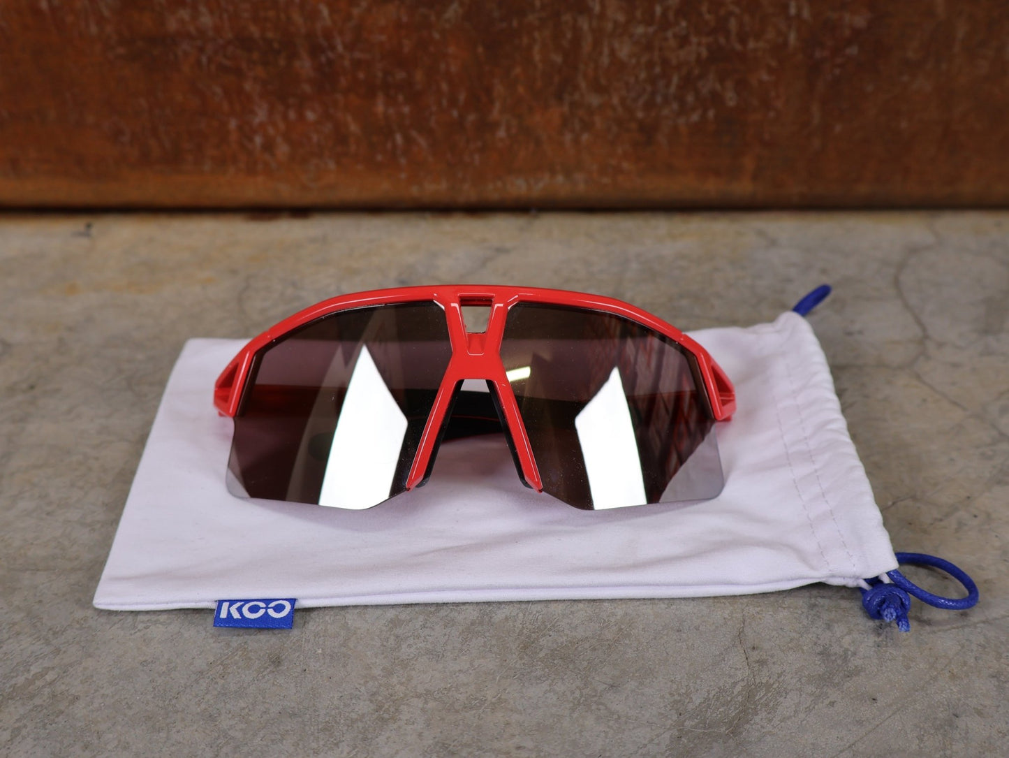 Brillen von Koo, KOO RED BULL - BORA HANSGROHE HYPE SONNENBRILLE / LEADER EDITION ROT vor USEDBIKES - OB.DE Hintergrund