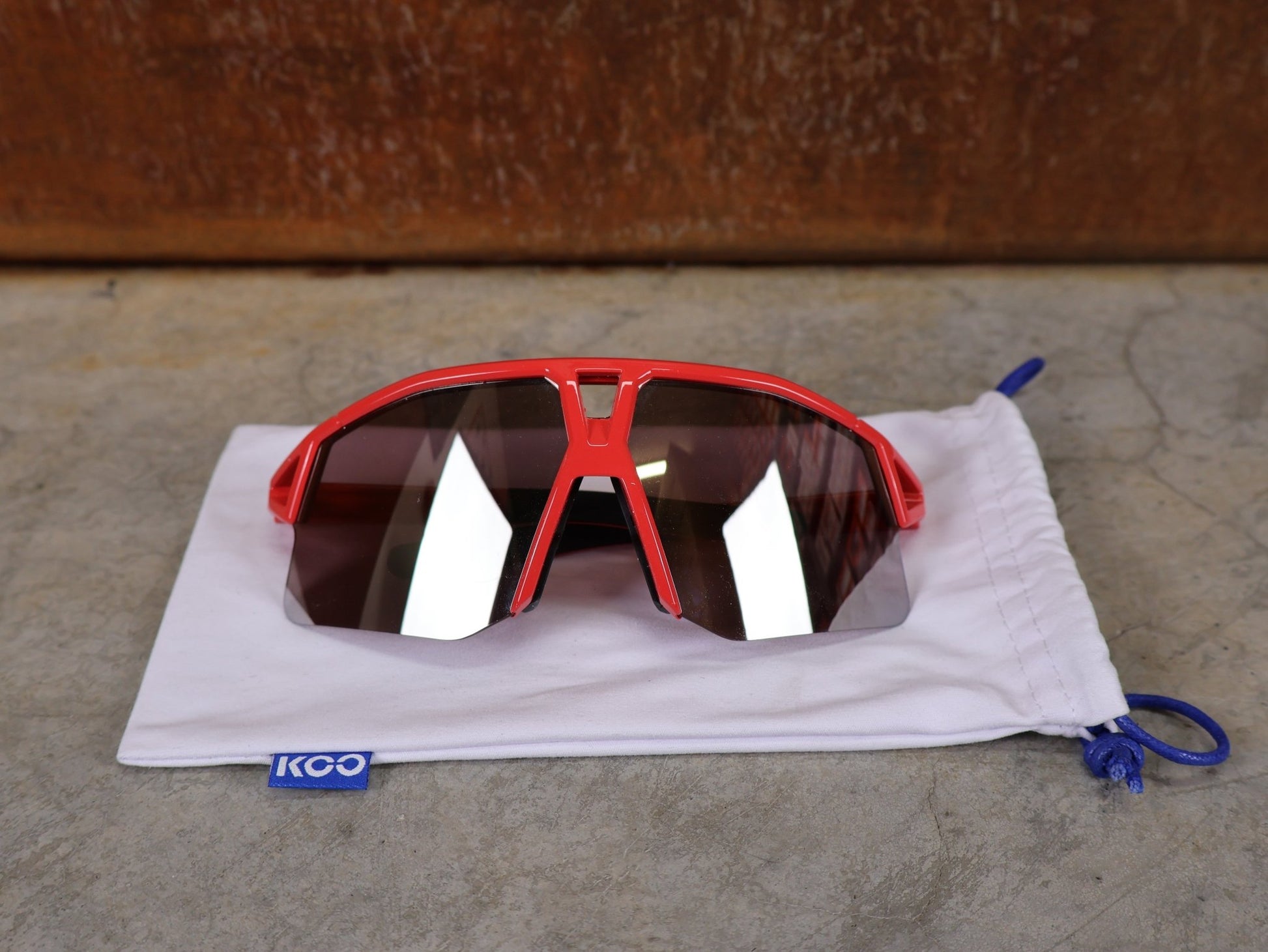 Brillen von Koo, KOO RED BULL - BORA HANSGROHE HYPE SONNENBRILLE / LEADER EDITION ROT vor USEDBIKES - OB.DE Hintergrund