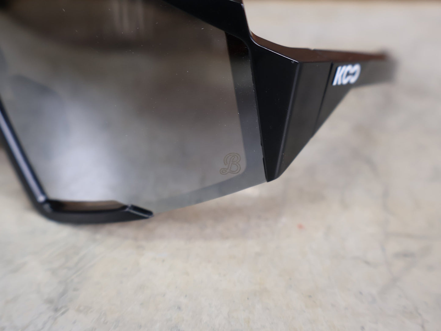 Brillen von Koo, KOO RED BULL - BORA HANSGROHE SPECTRO SONNENBRILLE / SCHWARZ GLANZ vor USEDBIKES - OB.DE Hintergrund