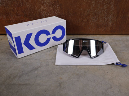 Brillen von Koo, KOO RED BULL - BORA HANSGROHE SPECTRO SONNENBRILLE / SCHWARZ GLANZ vor USEDBIKES - OB.DE Hintergrund