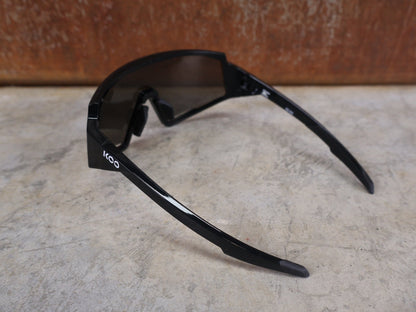 Brillen von Koo, KOO RED BULL - BORA HANSGROHE SPECTRO SONNENBRILLE / SCHWARZ GLANZ vor USEDBIKES - OB.DE Hintergrund