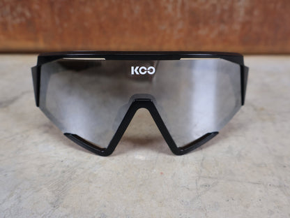 Brillen von Koo, KOO RED BULL - BORA HANSGROHE SPECTRO SONNENBRILLE / SCHWARZ GLANZ vor USEDBIKES - OB.DE Hintergrund