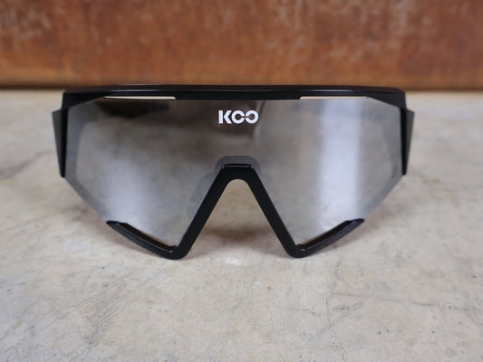 Brillen von Koo, KOO RED BULL - BORA HANSGROHE SPECTRO SONNENBRILLE / SCHWARZ GLANZ vor USEDBIKES - OB.DE Hintergrund