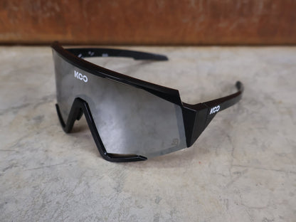 Brillen von Koo, KOO RED BULL - BORA HANSGROHE SPECTRO SONNENBRILLE / SCHWARZ GLANZ vor USEDBIKES - OB.DE Hintergrund