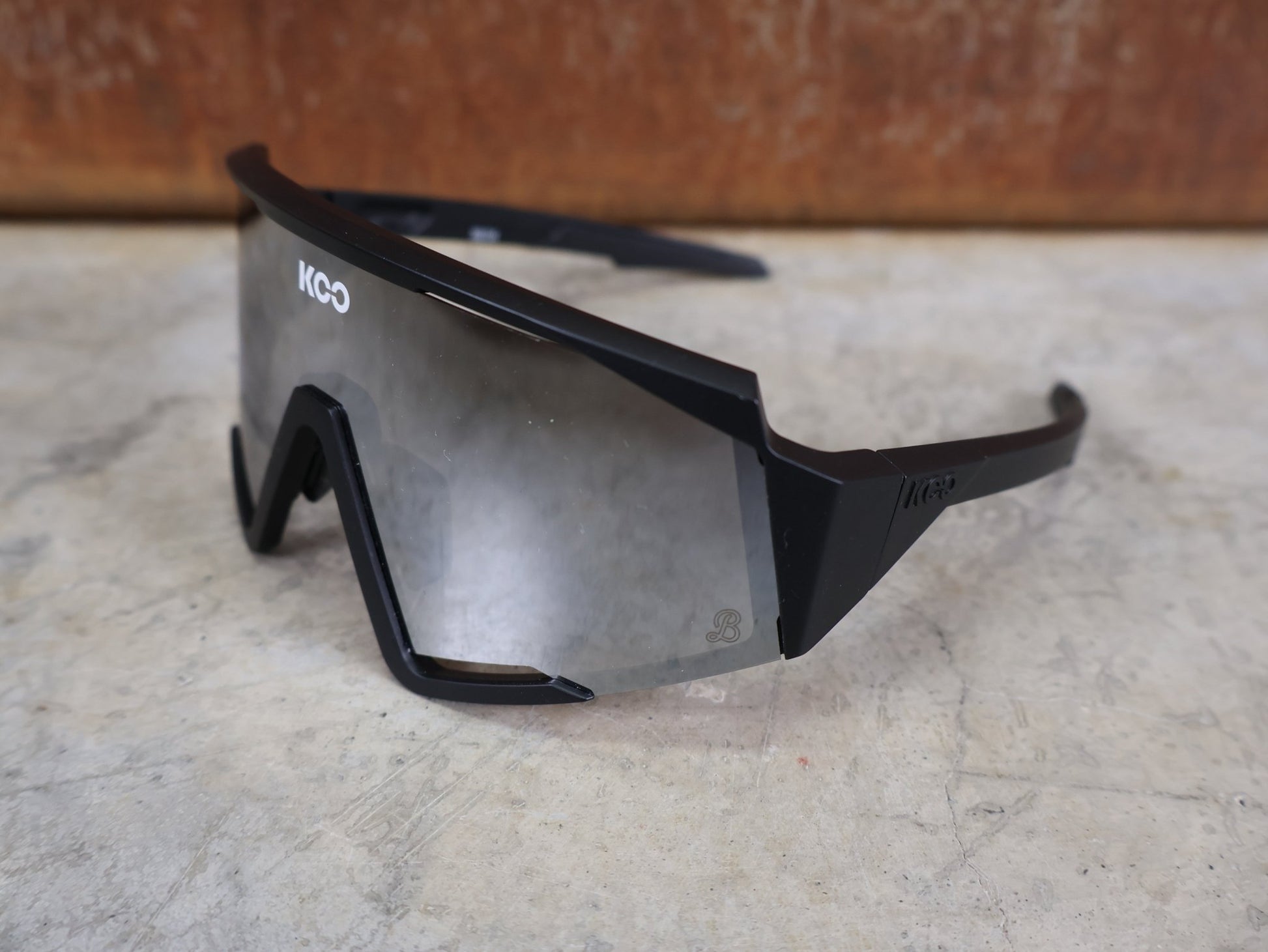 Brillen von Koo, KOO RED BULL - BORA HANSGROHE SPECTRO SONNENBRILLE / SCHWARZ MATT vor USEDBIKES - OB.DE Hintergrund