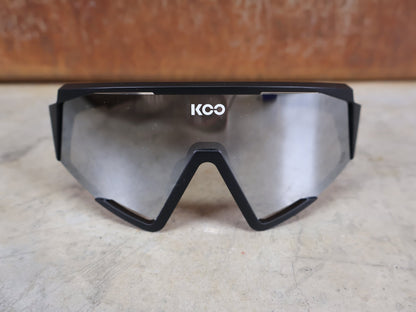 Brillen von Koo, KOO RED BULL - BORA HANSGROHE SPECTRO SONNENBRILLE / SCHWARZ MATT vor USEDBIKES - OB.DE Hintergrund