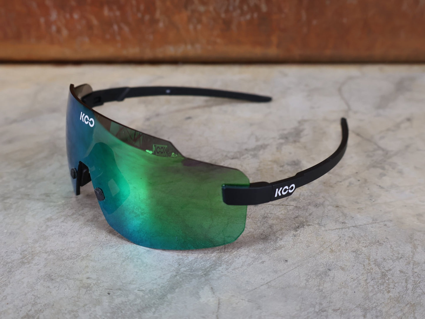 Brillen von Koo, KOO SUPERNOVA SONNENBRILLE / BLACK MATT GREEN MIRROR vor USEDBIKES - OB.DE Hintergrund