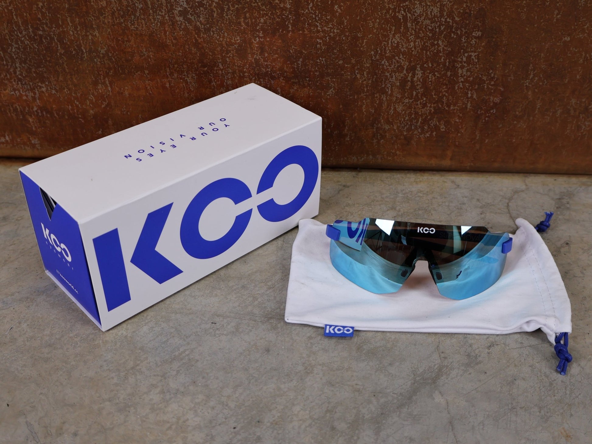 Brillen von Koo, KOO SUPERNOVA SONNENBRILLE / BLUE MATT TURQUOISE MIRROR vor USEDBIKES - OB.DE Hintergrund