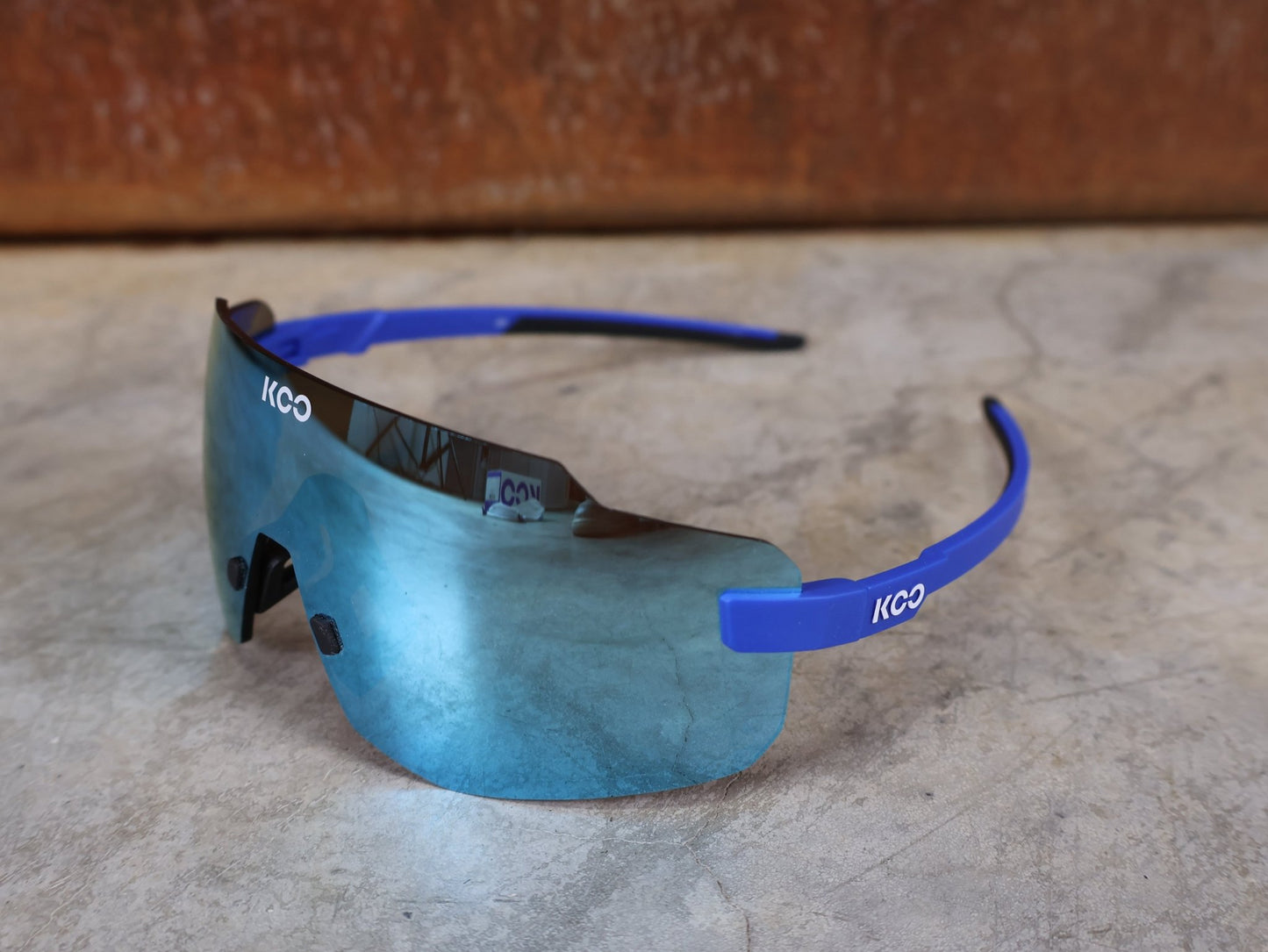 Brillen von Koo, KOO SUPERNOVA SONNENBRILLE / BLUE MATT TURQUOISE MIRROR vor USEDBIKES - OB.DE Hintergrund