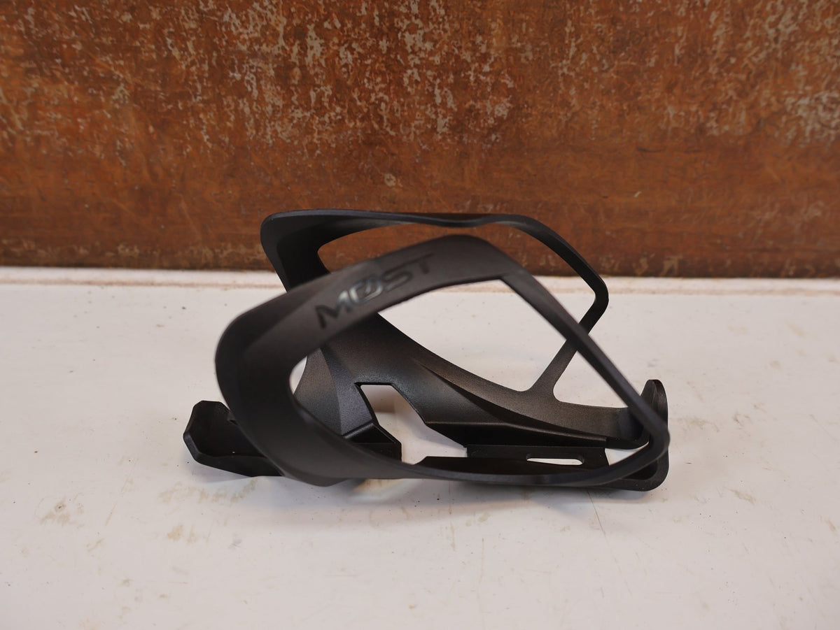 Trinkflaschen und Halter von Most, MOST TRAP PACF FLASCHENHALTER CARBON SCHWARZ 31G vor USEDBIKES-OB.DE Hintergrund